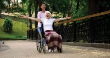 Don’t Let Limited Mobility Stop You From Being Active . Picture of a young asian female pushing an older caucasian female in a wheelchair.